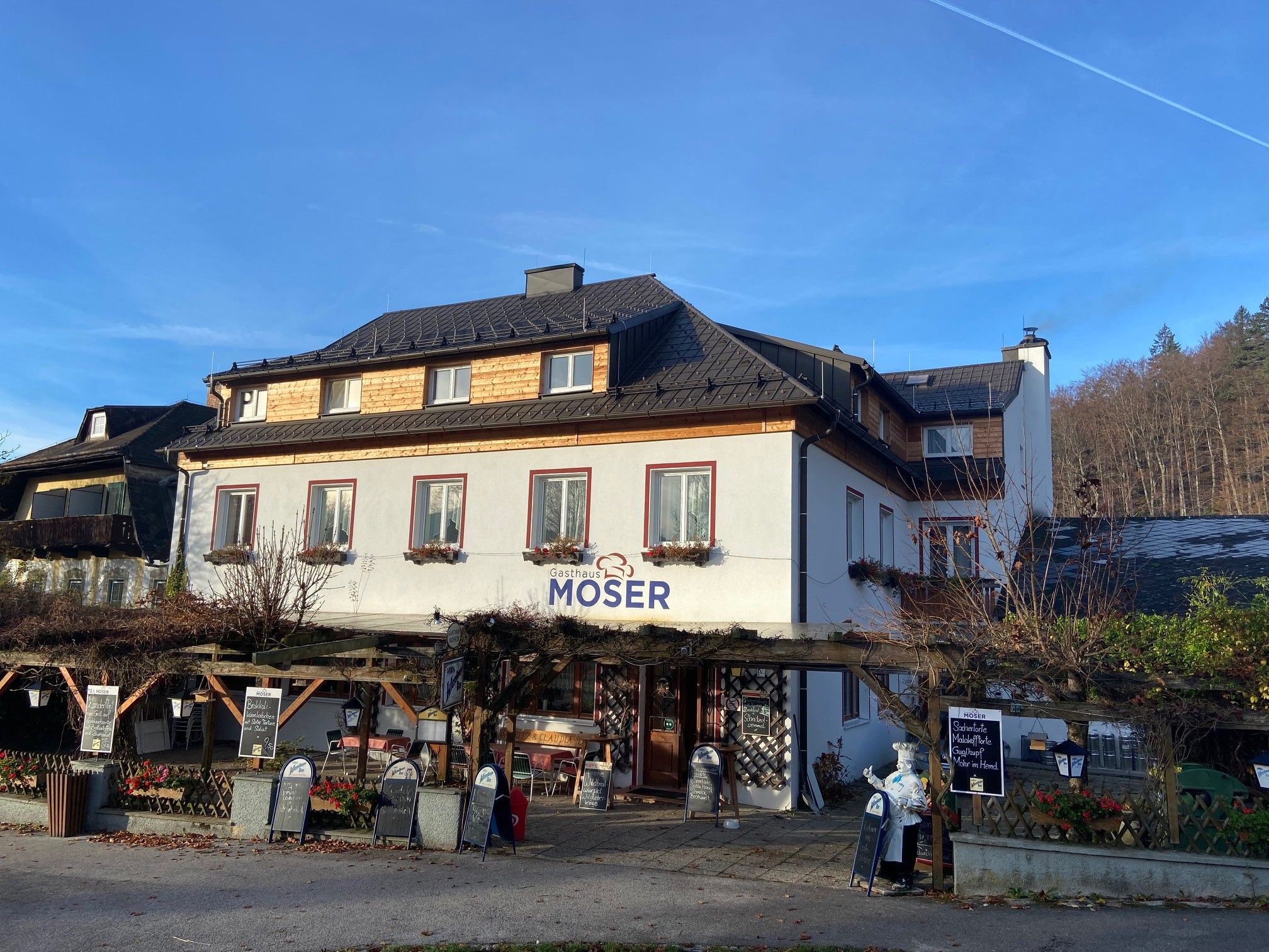 Gasthaus Moser mit Terrasse und blauen Himmel im Hintergrund.