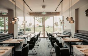 Modernes Restaurant mit eleganter Einrichtung und großen Fenstern.