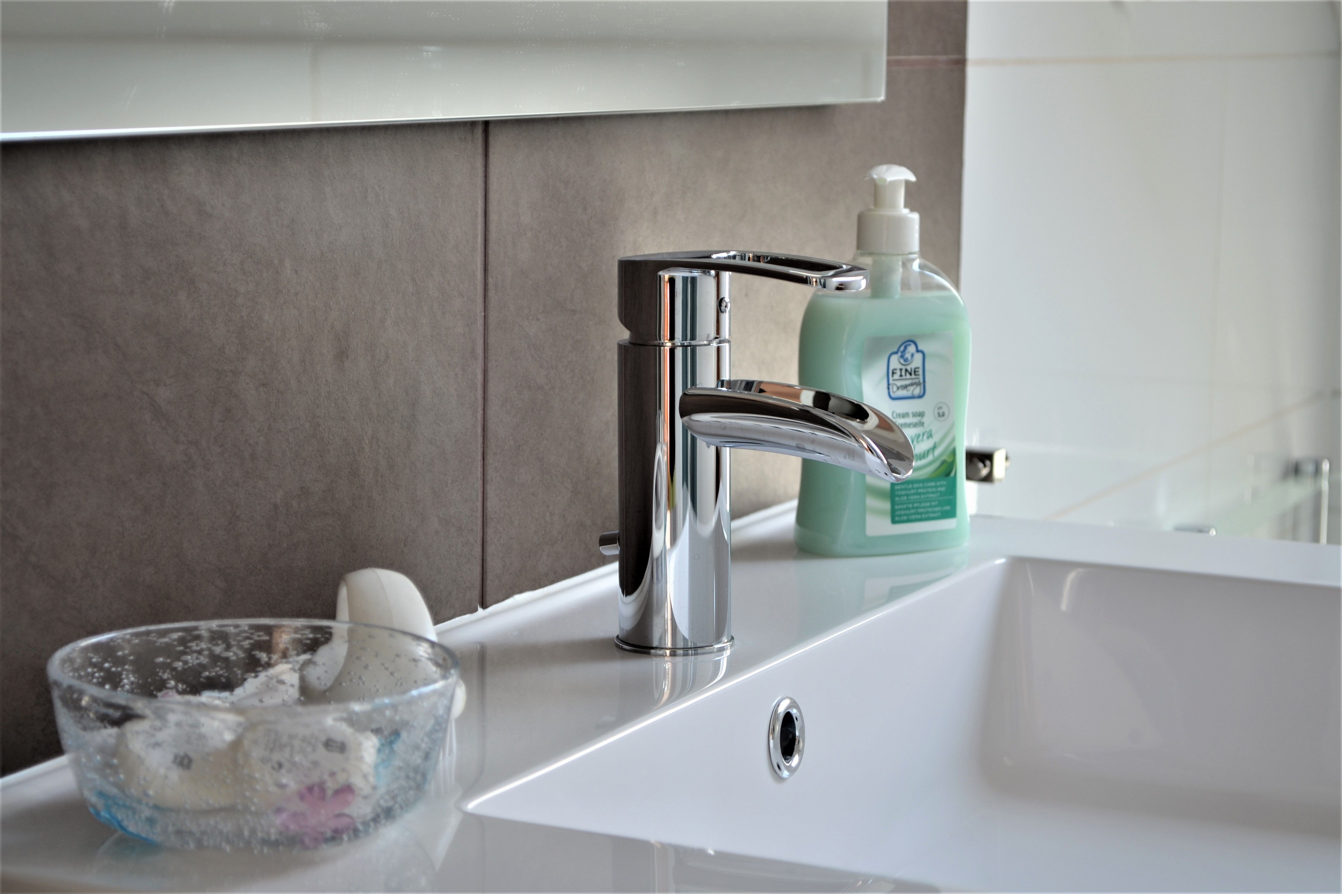Nahaufnahme eines Waschbeckens mit Seifenspender und Glas mit Seife.