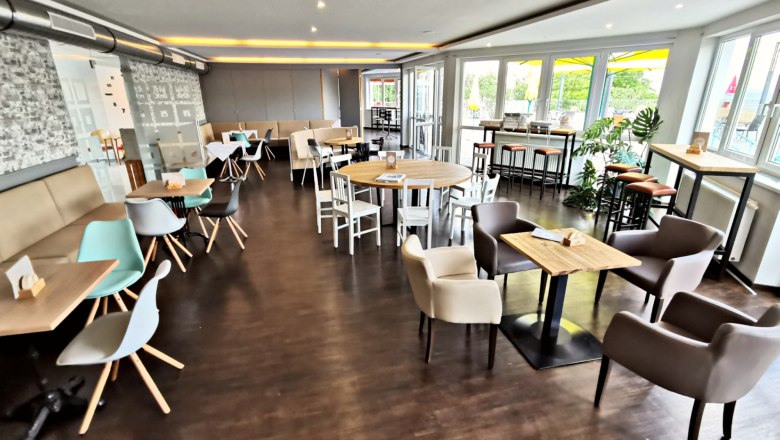 Interior view of a modern café with wooden floor, tables and chairs.