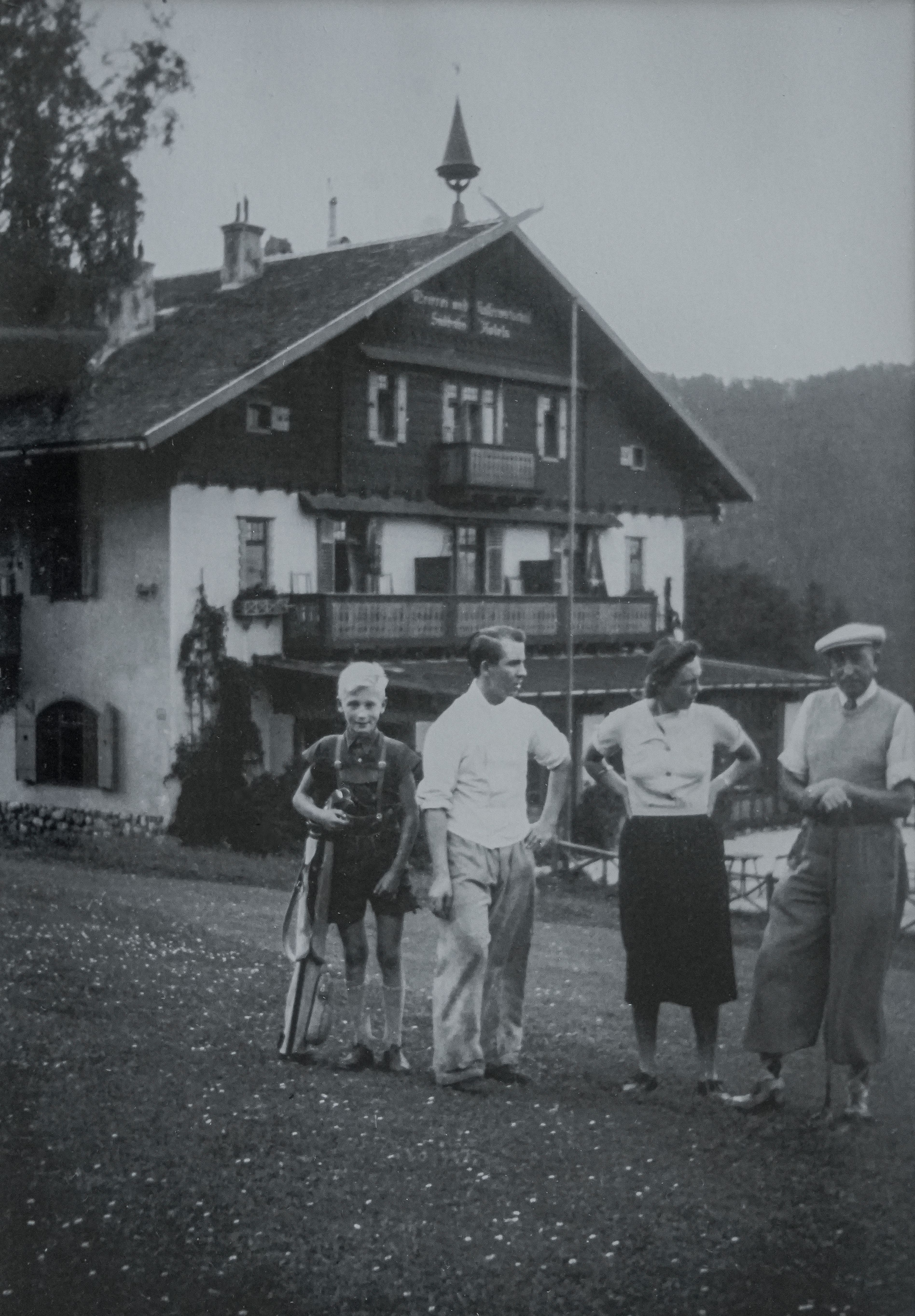 vier Personen mit Golfkleidung und Ausrüstung stehen auf dem Golfplatz vor einem Gebäude