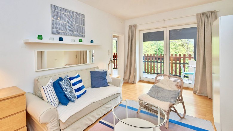 Modern living room with sofa, cushions, glass table and balcony.