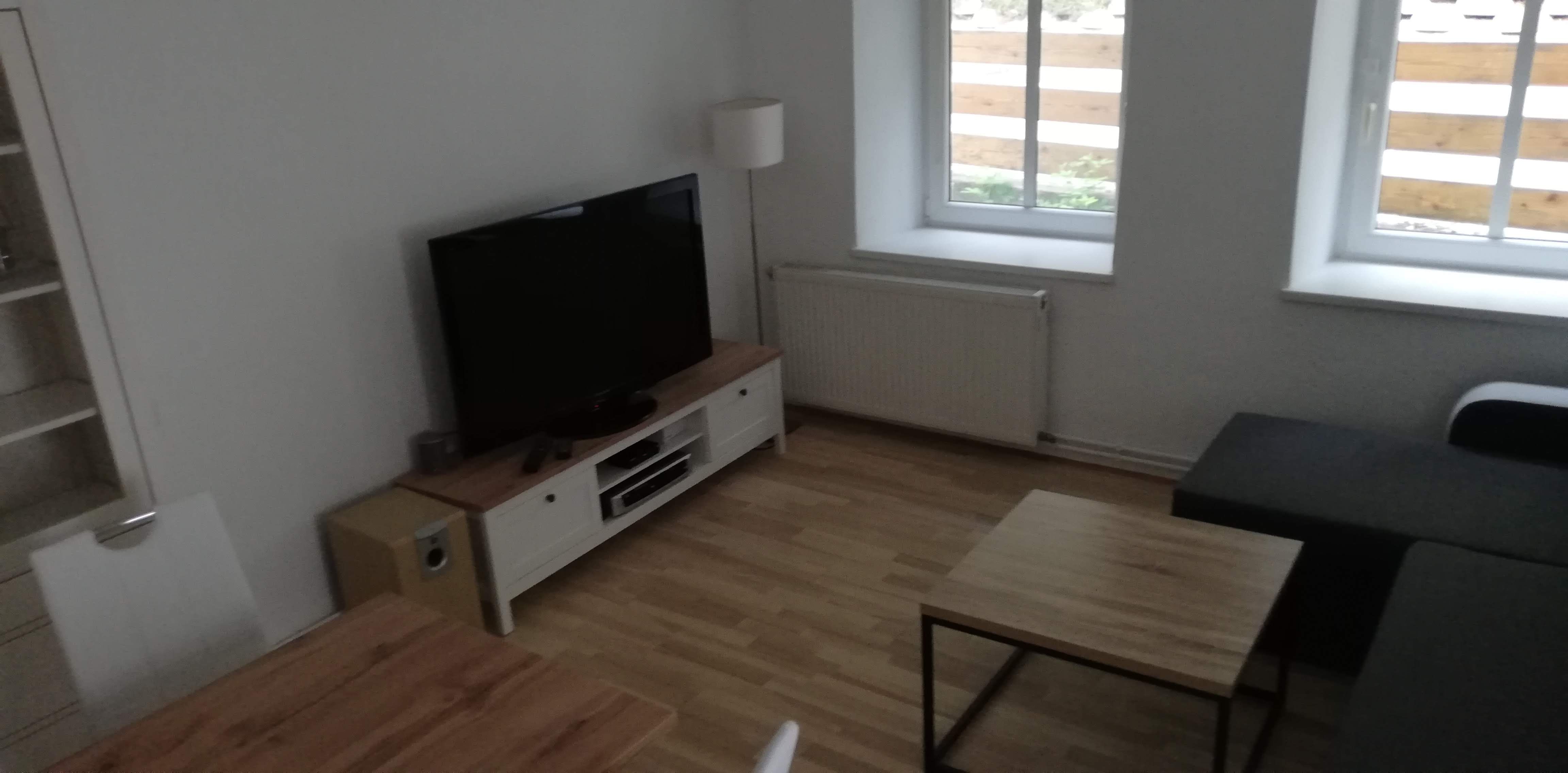 Modernes Wohnzimmer mit Fernseher, Sofa und Holztisch.