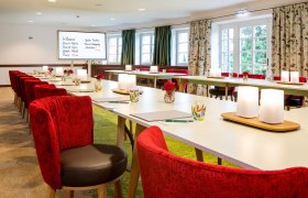 Elegant seminar room with red chairs and white tables.