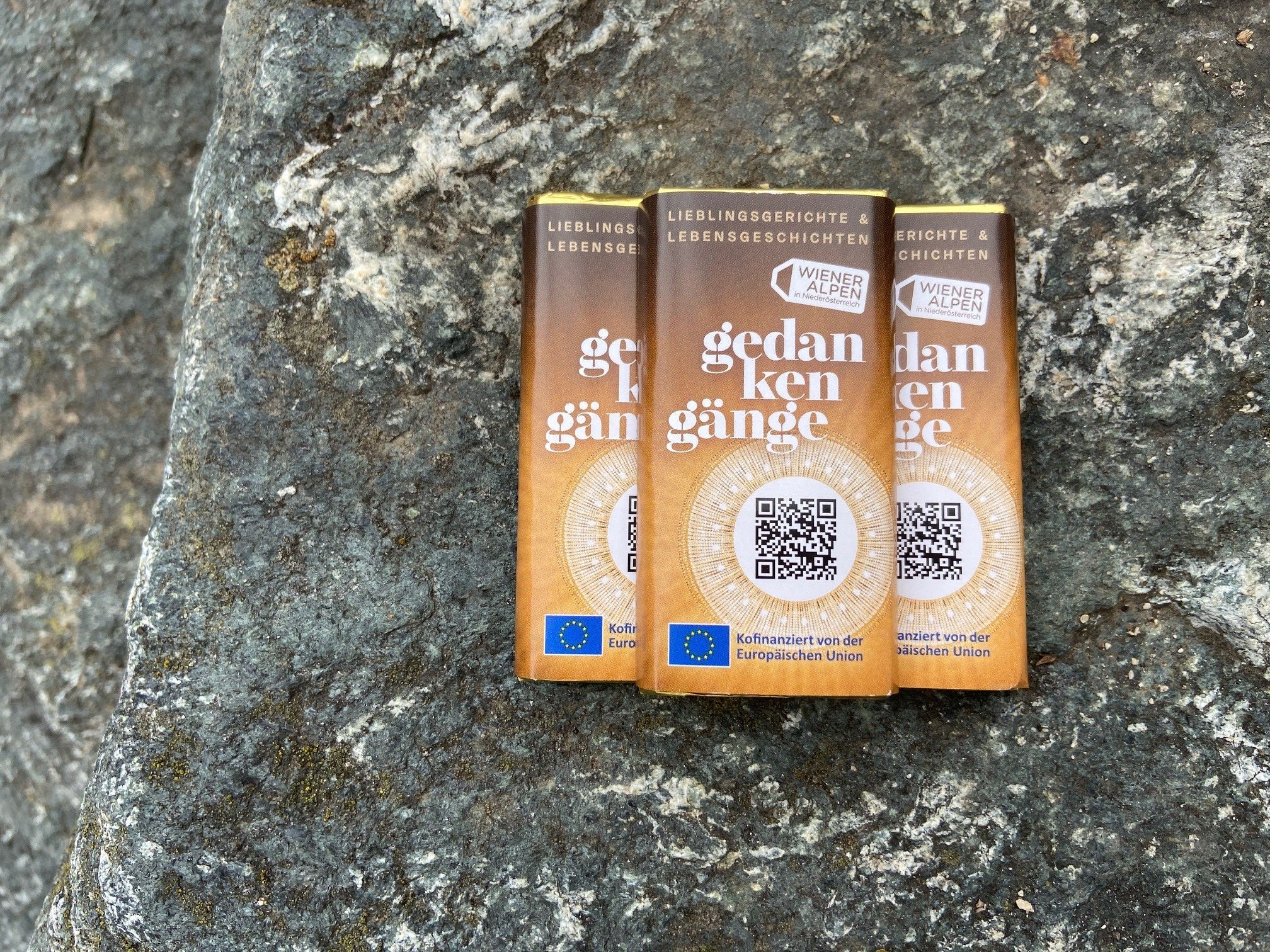 Drei kleine Lindt Schokotafeln mit mit Gedanken-Gänge Branding liegen auf einem Steinhintergrund