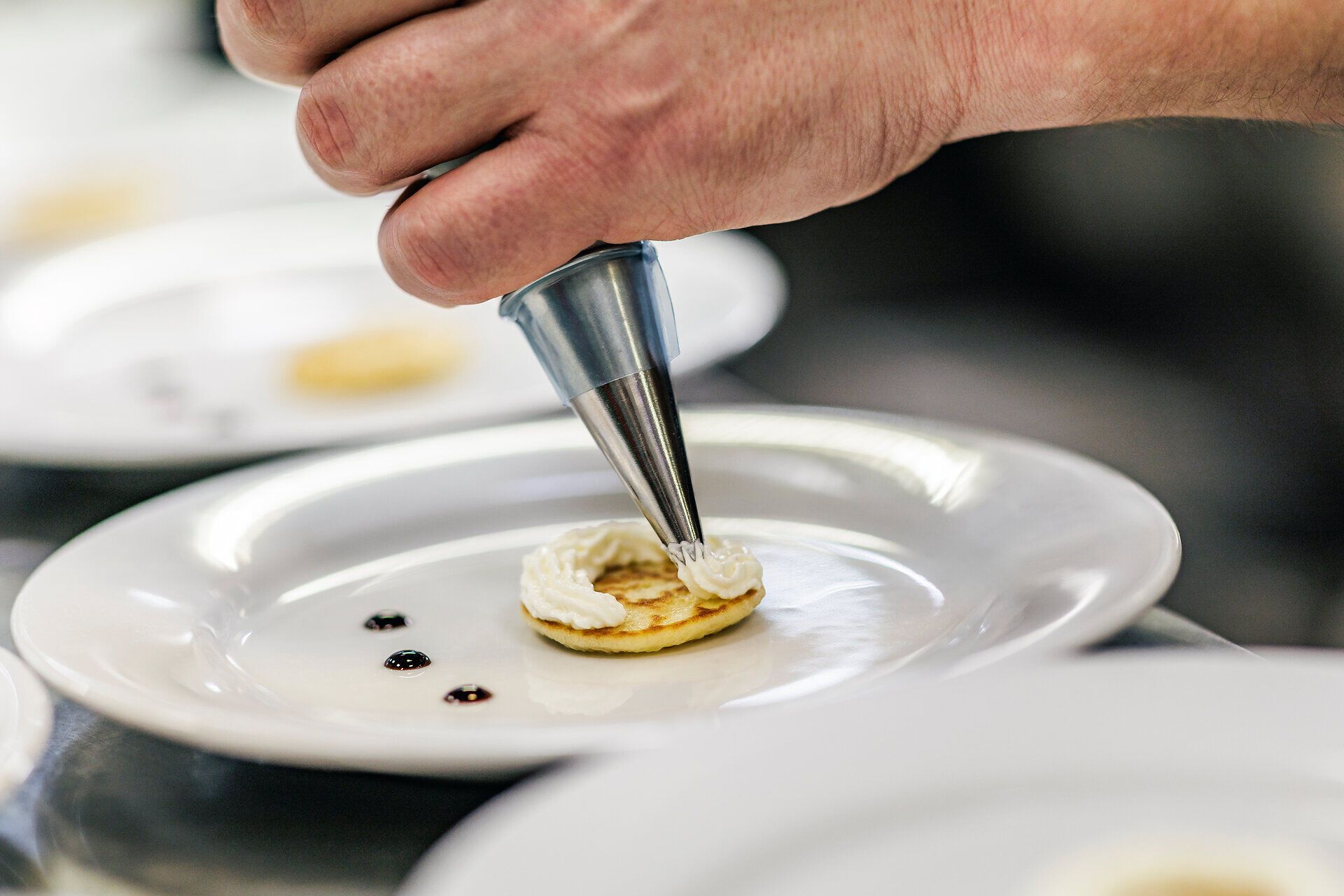 Ein kunstvoll angerichteter Teller vereint die Aromen der Region. Der knusprige Backteig umhüllt zarten Karpfen, während die Mie-Nudeln und das Wurzelgemüse harmonisch dazu serviert werden. Ein Fest für die Sinne, das die kulinarische Vielfalt der Wiener Alpen widerspiegelt.
