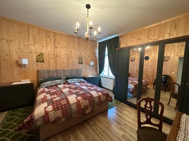 Gemütliches Schlafzimmer mit Holzwänden, Doppelbett, Spiegelkleiderschrank und Kronleuchter.