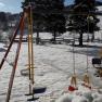 Snow-covered playground with swings and trees in the background.
