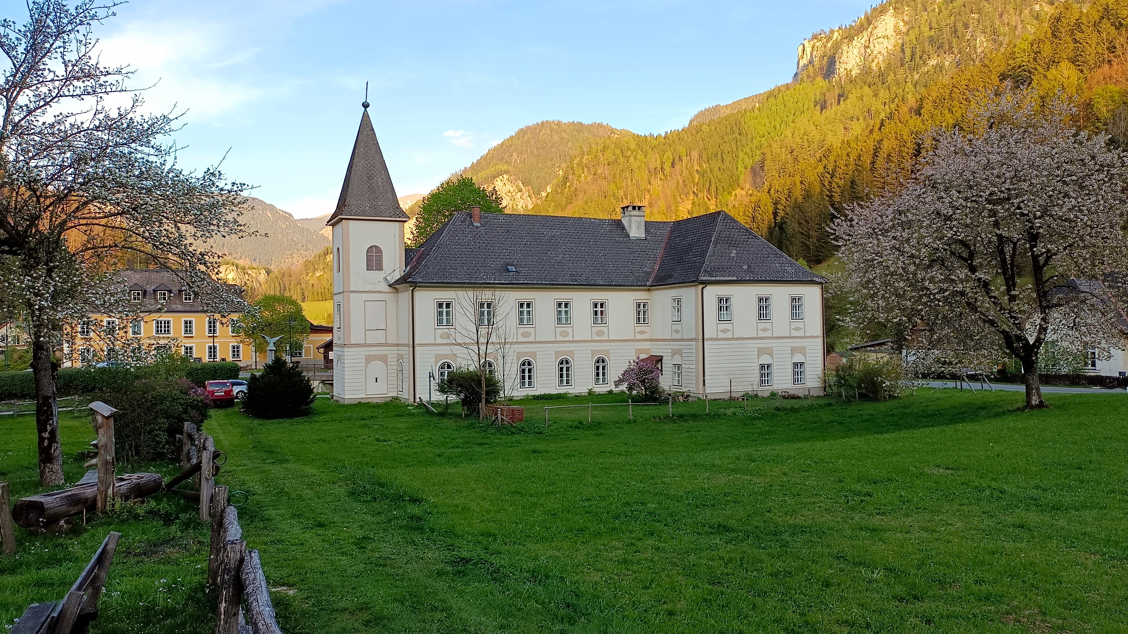 Evangelische Pfarrkirche Nasswald mit cremefarbener Fassade und Rundbogenfenstern, davor grüne Wiese