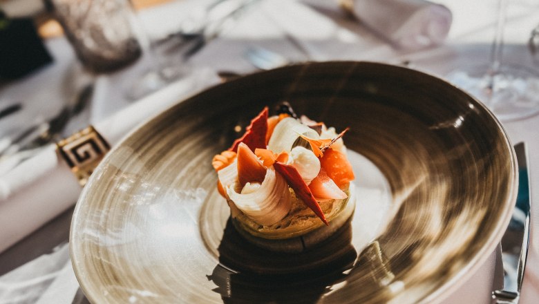 Ein kunstvoll angerichtetes Gericht auf einem braunen Teller in einem Restaurant.