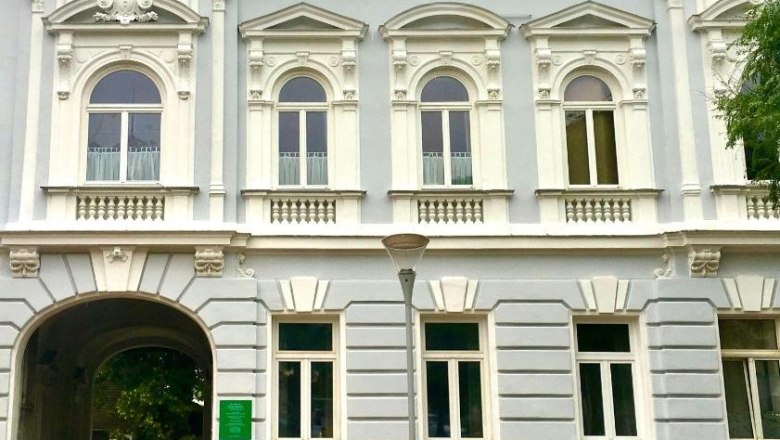 Historisches Gebäude mit verzierten Fenstern und einem Torbogen.