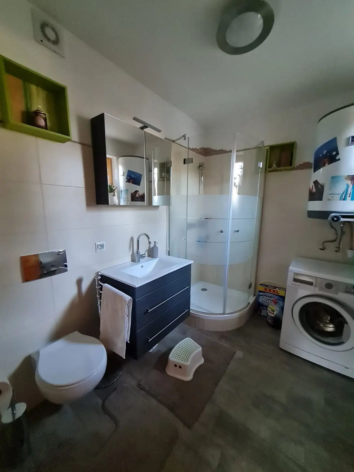 Modernes Badezimmer mit Dusche, Waschbecken, Toilette und Waschmaschine.