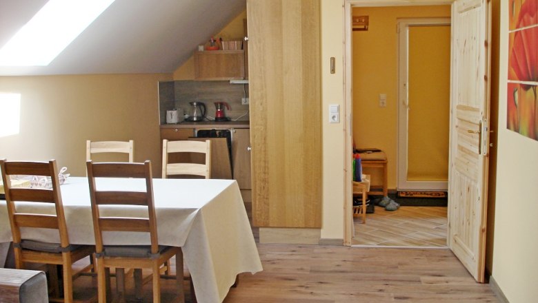 Dining area of a vacation apartment with table, chairs and kitchenette.