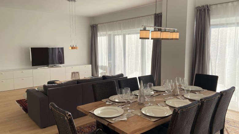 Moderner Wohn-Essbereich mit Esstisch, Stühlen, Sofa und Fernseher.