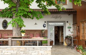 Entrance to a country inn with wooden furniture and plants.