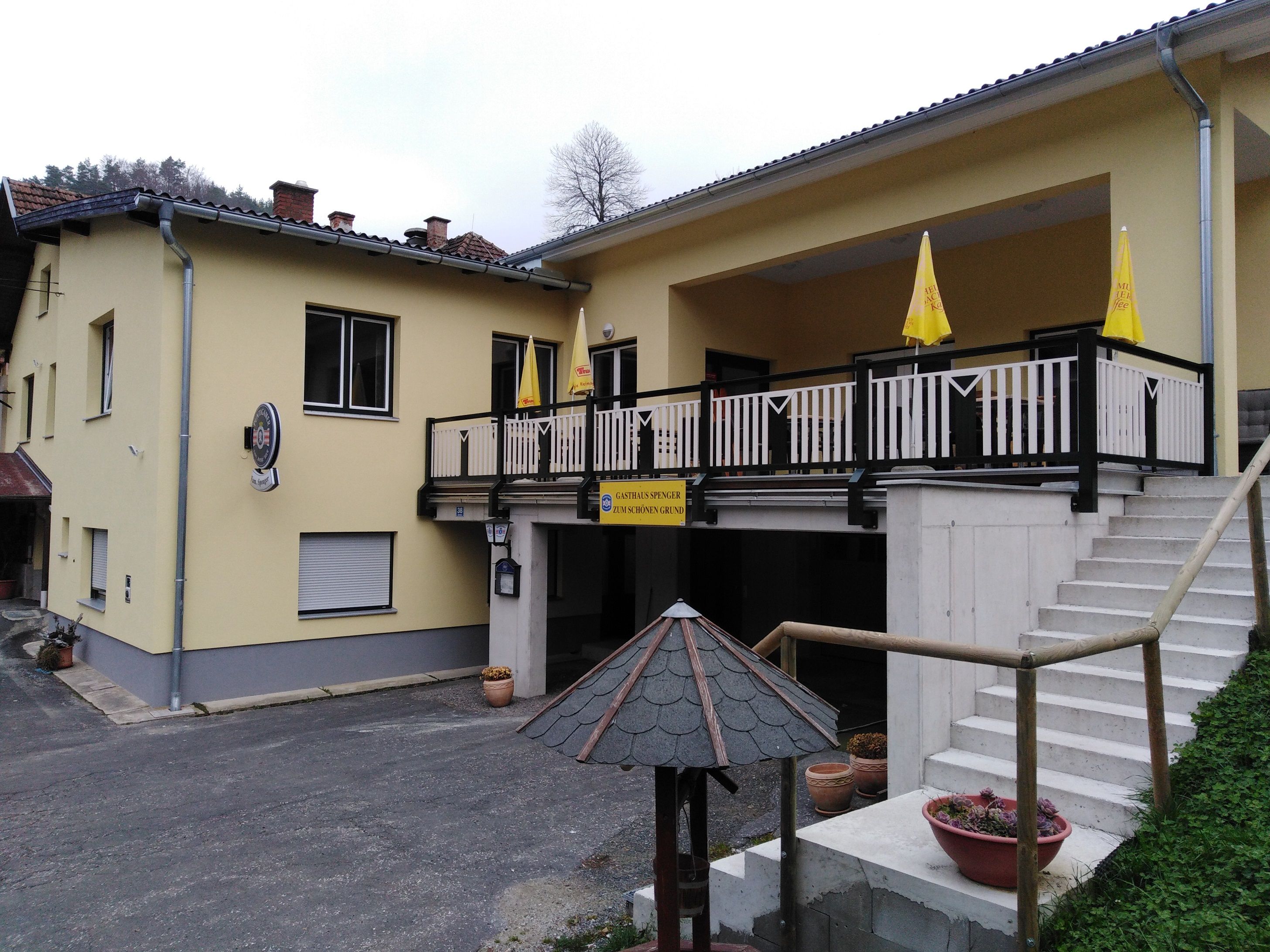 Gelbes Gasthaus mit Terrasse und Treppe.