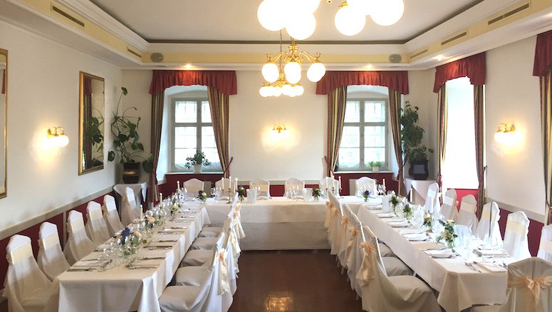 Elegant hall in Gloggnitz Castle, decorated for a banquet with white tablecloths and chairs.