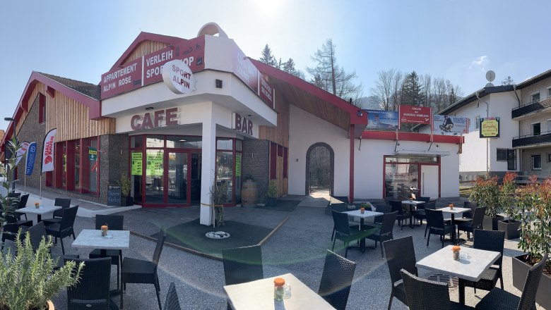 Außenansicht einer Café-Bar mit Terrasse und Sitzgelegenheiten im Freien.