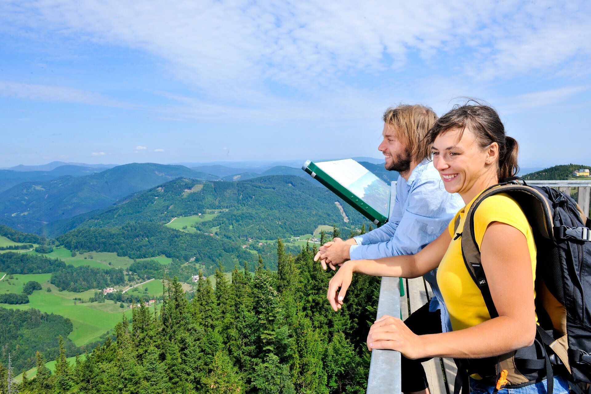 Die atemberaubende Aussicht von der Aussichtsplattform lässt das Herz eines jeden Naturfreundes höher schlagen. Umgeben von üppigen Wäldern und sanften Hügeln, genießen die Wanderer die frische Bergluft und die Ruhe der Natur. Ein perfekter Ort, um die Schönheit des Sommers in den Bergen zu erleben.