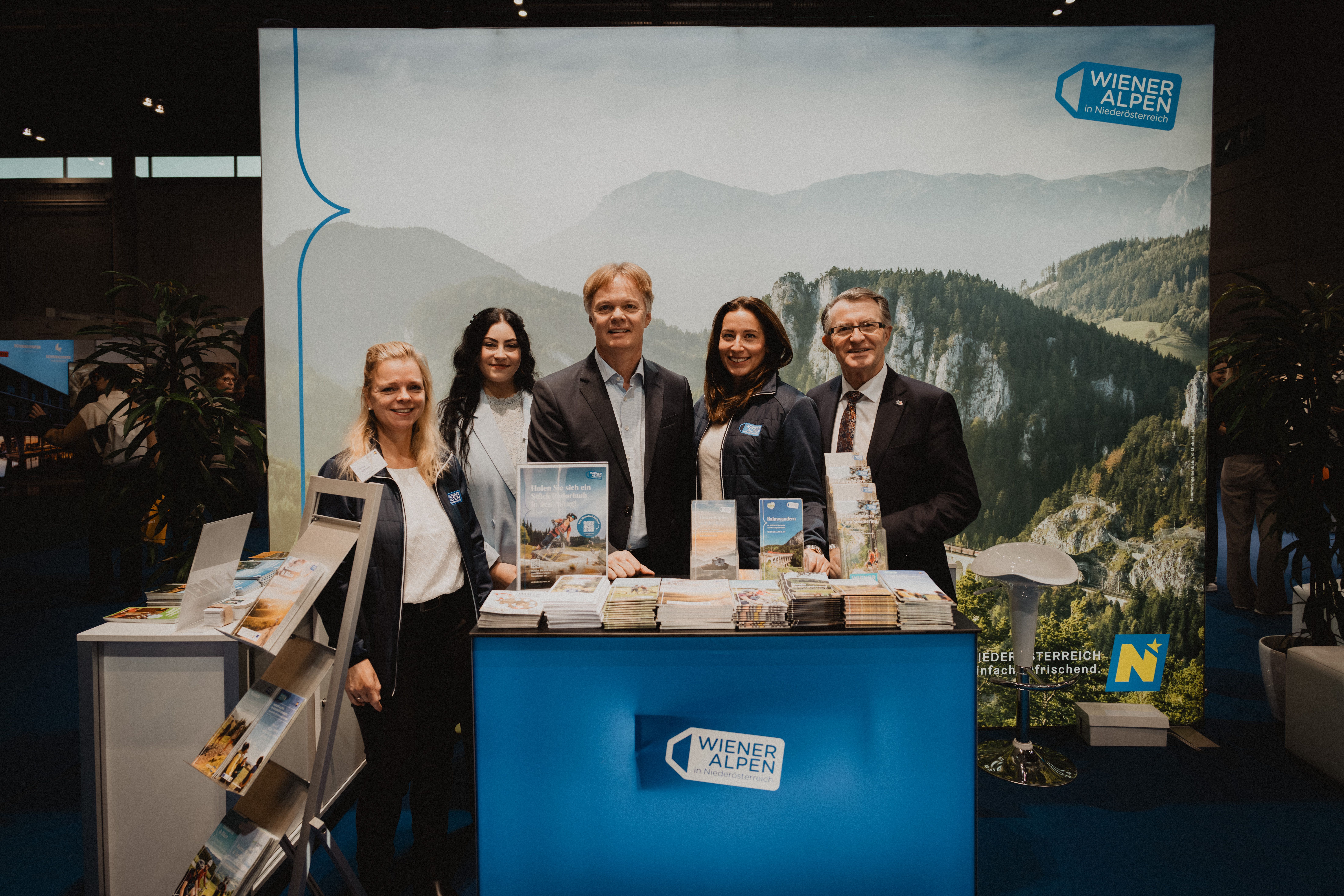 Drei Damen und zwei Herren vor dem Wiener Alpen Stand 