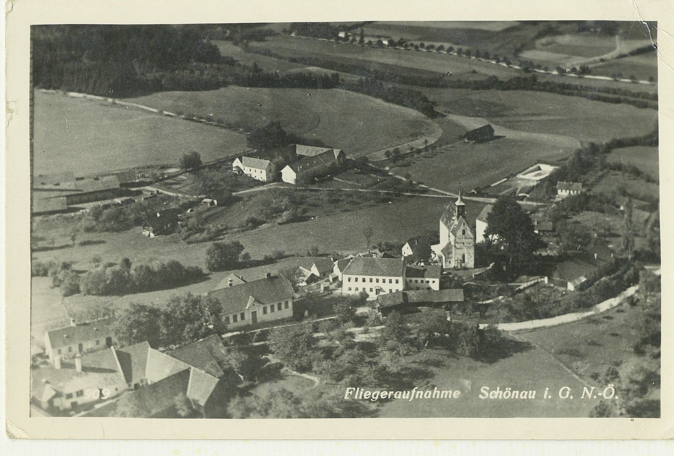 Eine alte, schwarz-weiße Luftaufnahme von Bad Schönau mit Wehrkirche und wenigen Häusern
