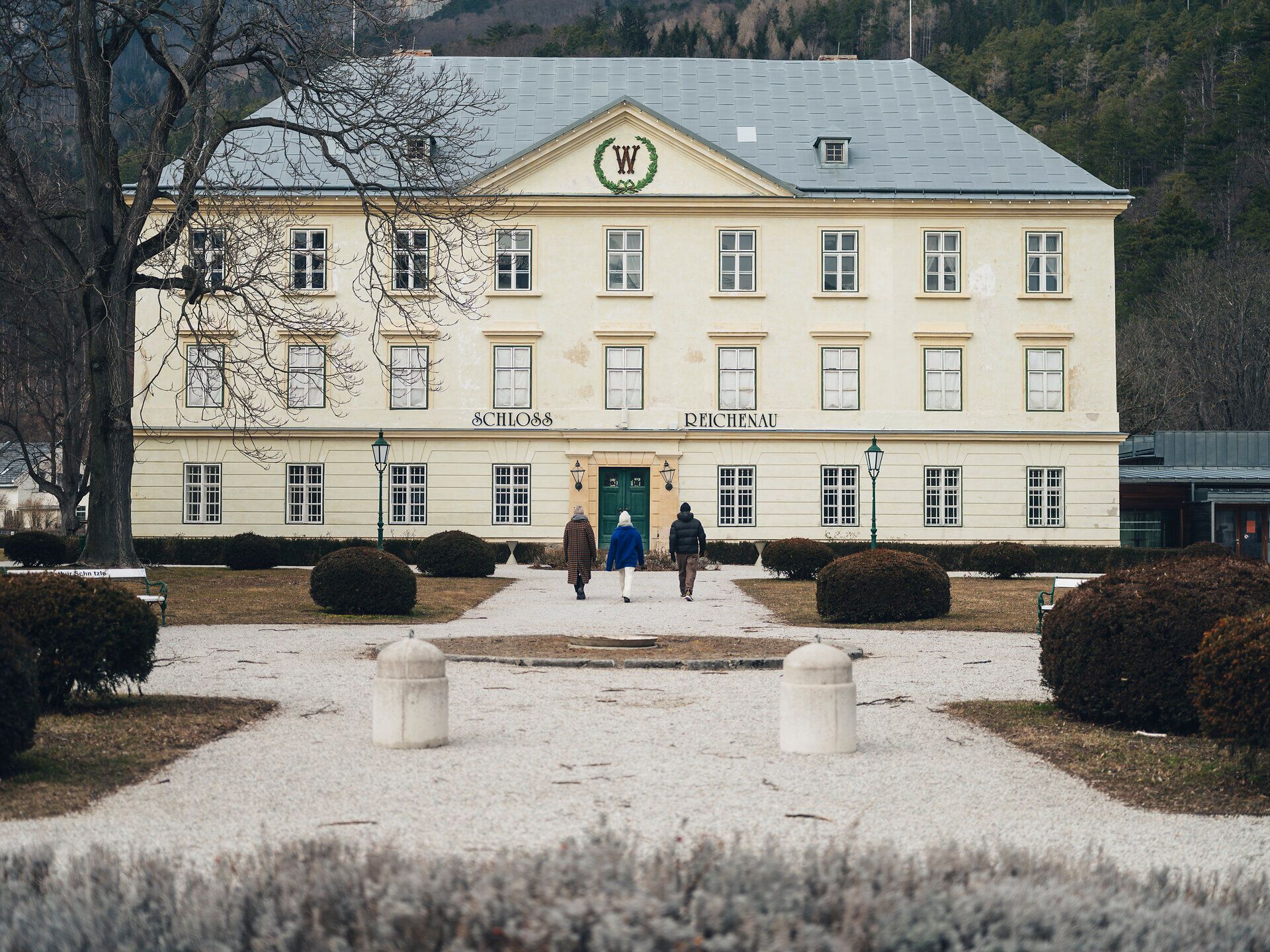 Umgeben von einer malerischen Winterlandschaft, strahlt das Schloss Reichenau eine zeitlose Eleganz aus. Die schneebedeckten Sträucher und der klare Himmel schaffen eine friedliche Atmosphäre, die zum Verweilen einlädt. Ein perfekter Ort, um die winterliche Schönheit der Wiener Alpen zu genießen.
