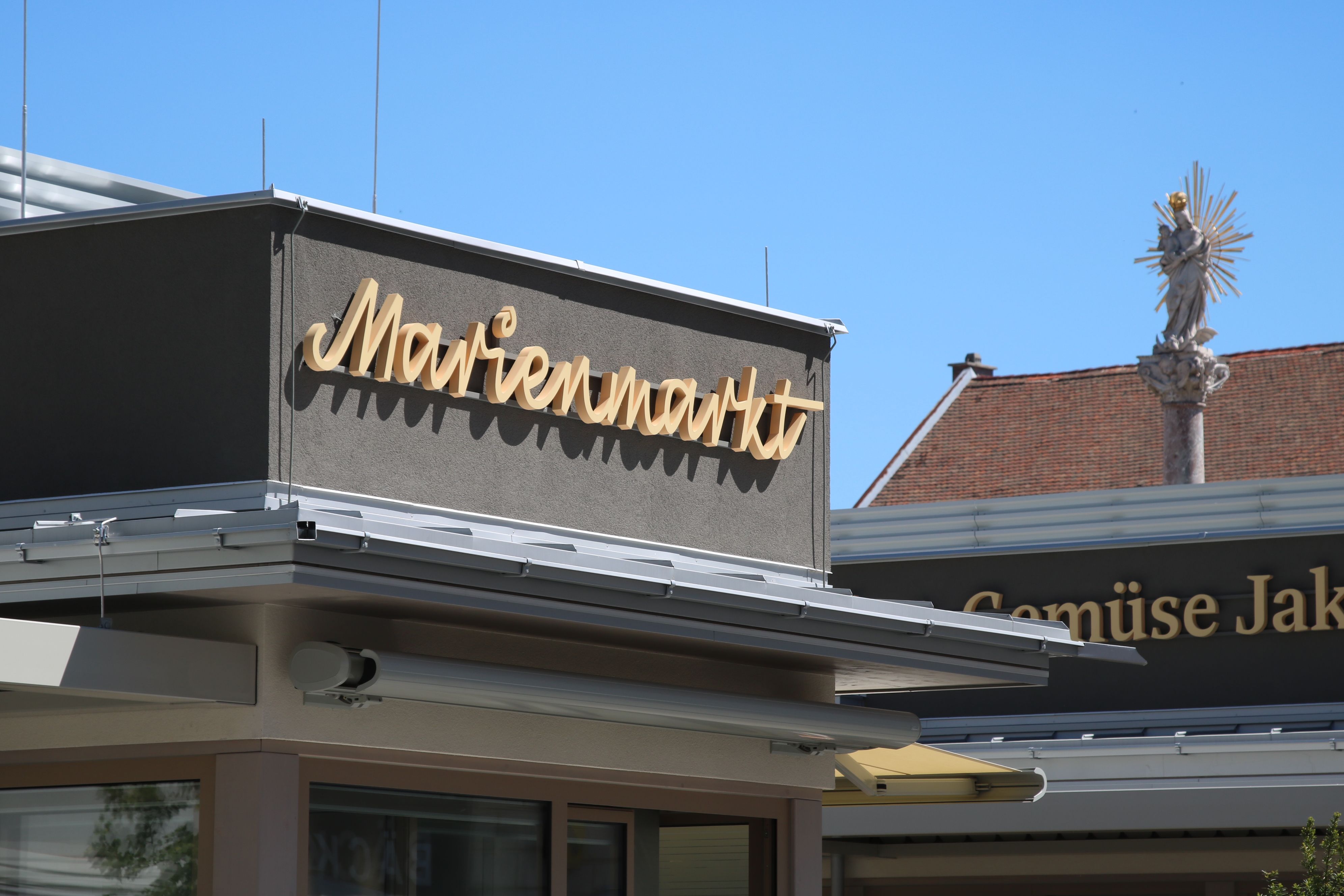 Logo vom Marienmarkt in Schreibschrift auf einem Hausdach. 