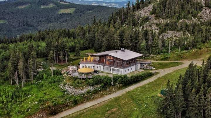 Luftaufnahme einer Berghütte inmitten von Wald und Bergen.