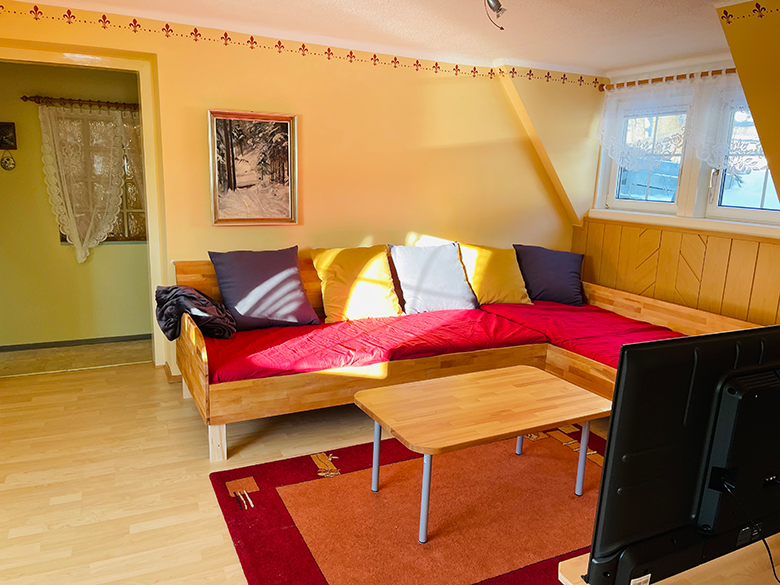 Living room with red sofa, wooden table and TV.