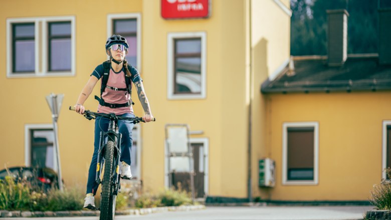 Person auf Fahrrad vor gelbem Gebäude mit ÖBB-Logo.
