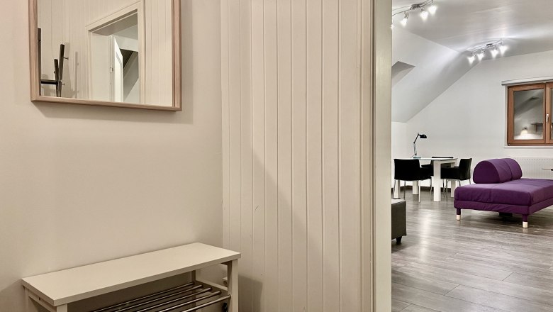 Innenansicht eines modernen Lofts mit lila Sofa und Esstisch.