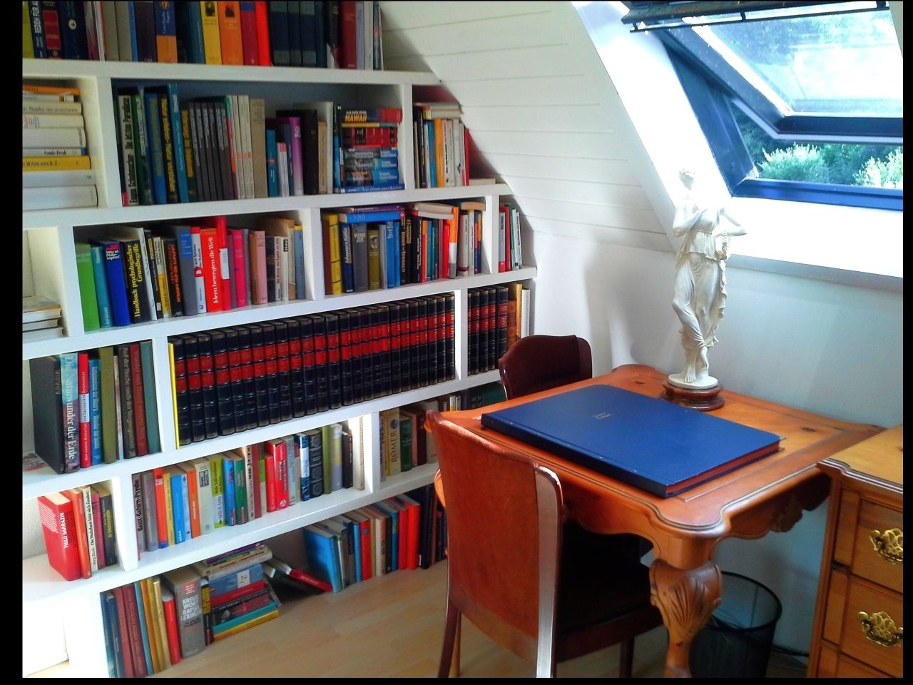 Ein gemütlicher Arbeitsbereich mit Bücherregal, Schreibtisch und Statue.