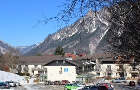 Exterior view of a building against a mountain backdrop with snow-covered peaks and a blue sky.