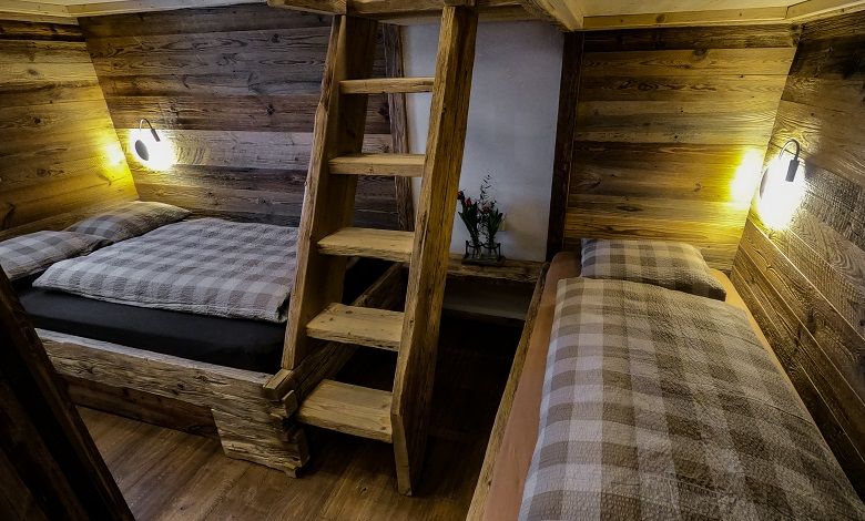 Innenansicht einer rustikalen Holzhütte mit zwei Betten und einer Holzleiter.