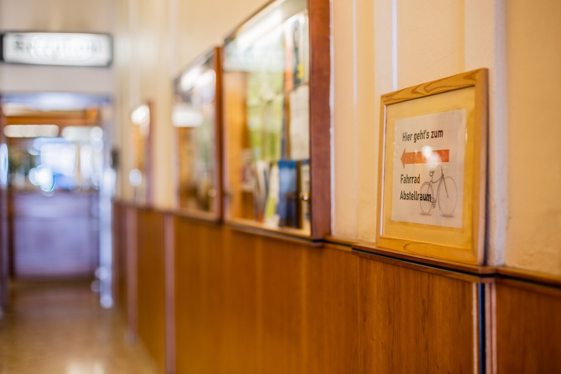 Ein Schild führt die Gäste vom Hotel Zentral durch einen teilweise holzvertäfelten Flur zum Fahrrad-Abstellraum.