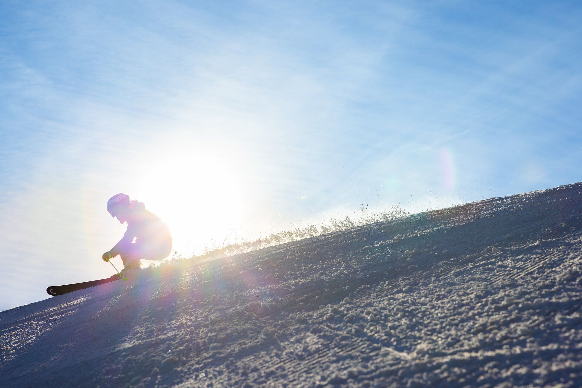 Ein Skifahrer gleitet elegant über die schneebedeckte Piste, während die Sonne strahlend am Himmel steht. Die frische Bergluft und der glitzernde Schnee schaffen eine magische Winterlandschaft, die zum Verweilen einlädt.