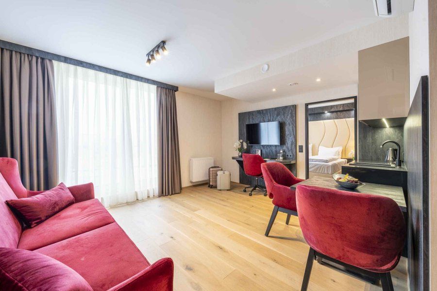 Modernes Hotelzimmer mit rotem Sofa, Schreibtisch und Fernseher.