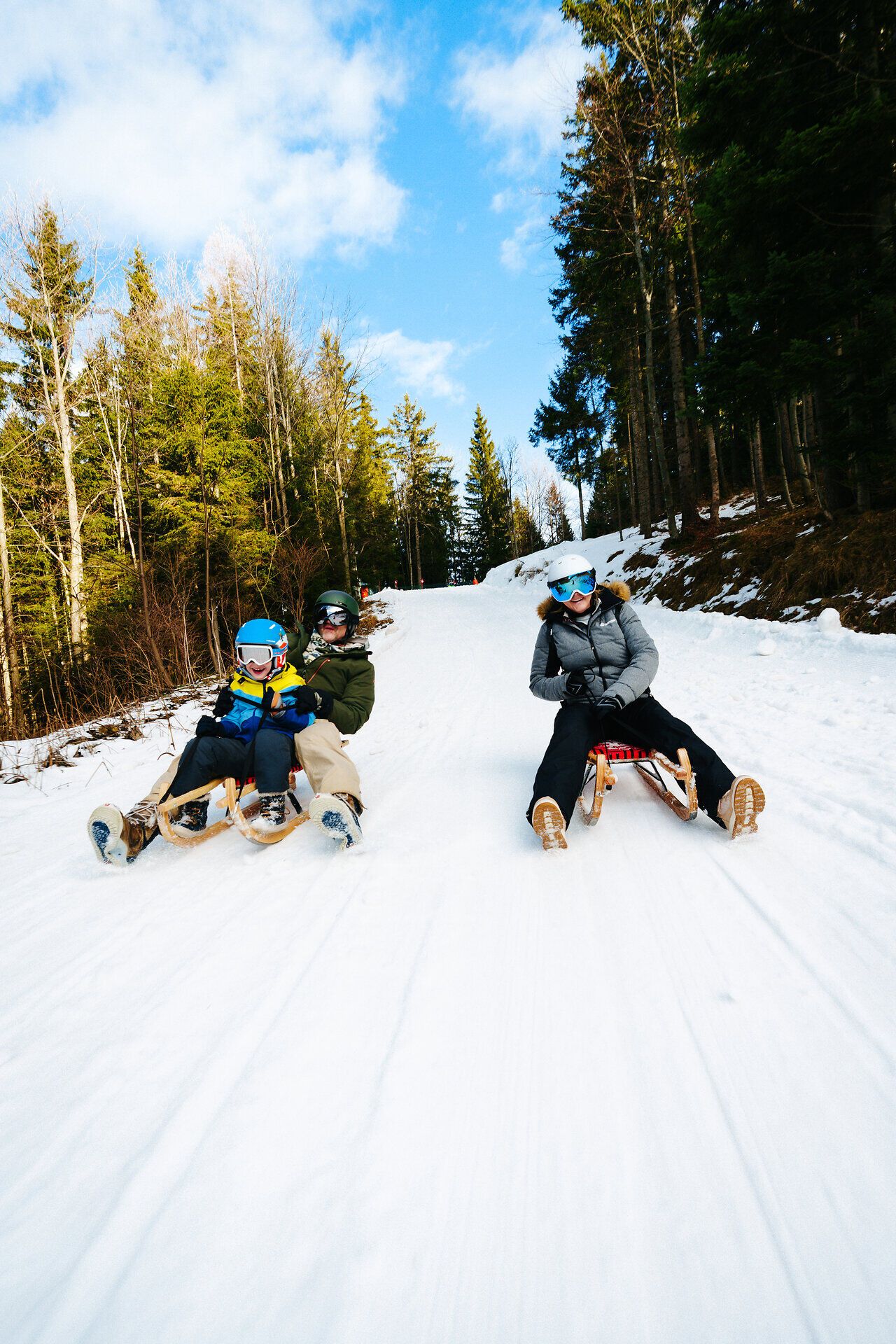 Familie beim Rodeln auf einer verschneiten Rodelbahn am Semmering Hirschenkogel.