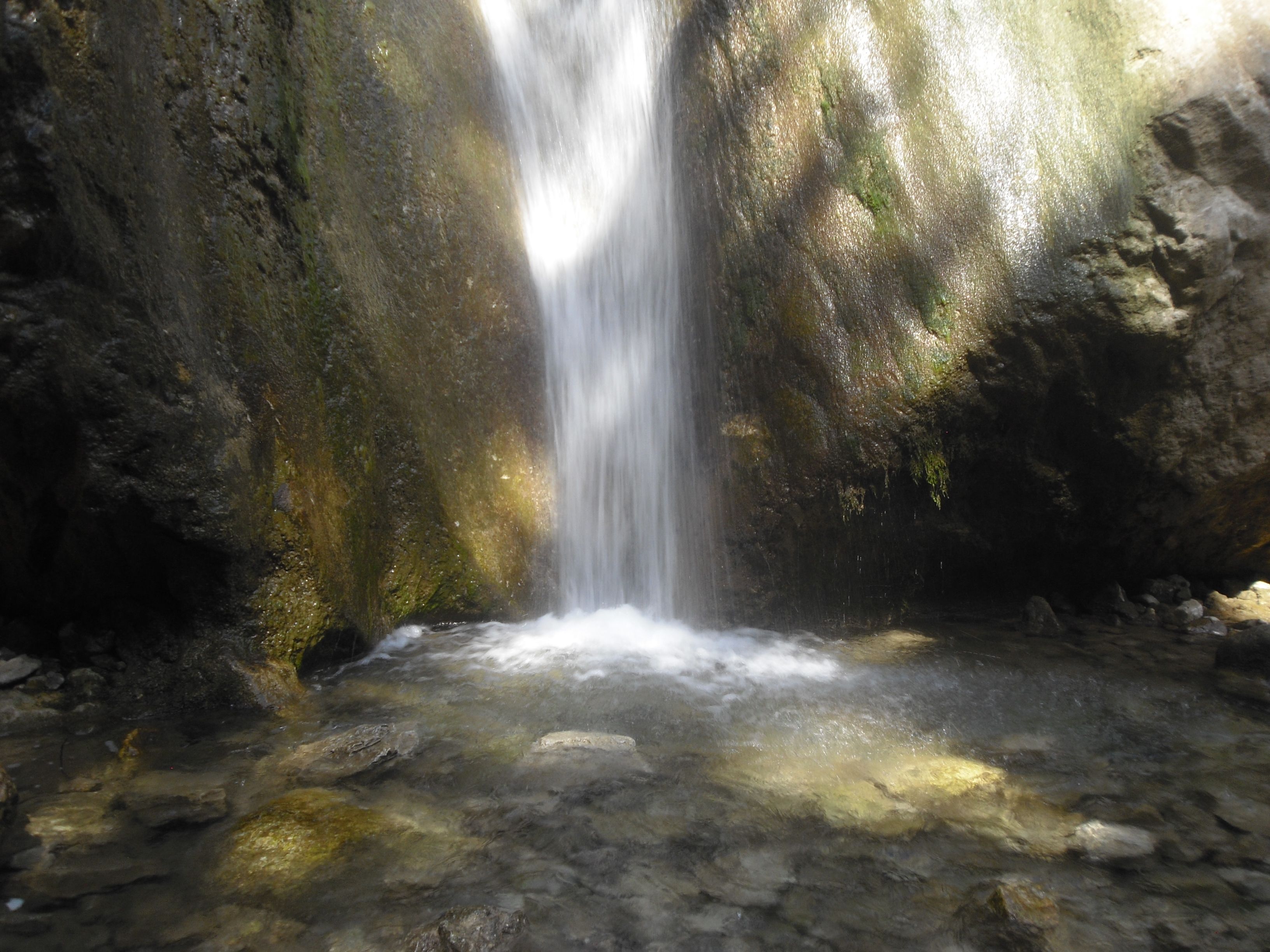 Wasserfall in einer felsigen Umgebung mit klarem Wasserbecken.