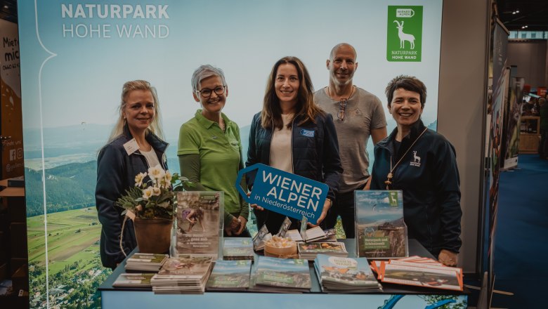 5 Menschen vor dem Naturpark Stand - mit Prospekten 