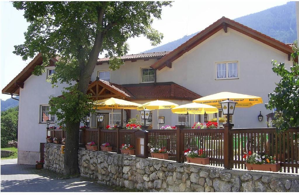 Gasthof mit Terrasse und gelben Sonnenschirmen.