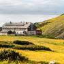 The Karl Ludwig House in an alpine landscape with yellow flower meadows and a cloudy sky.