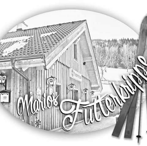 Schwarz-weiß Bild eines Holzhauses mit der Aufschrift 'Marios Futterkrippe'.