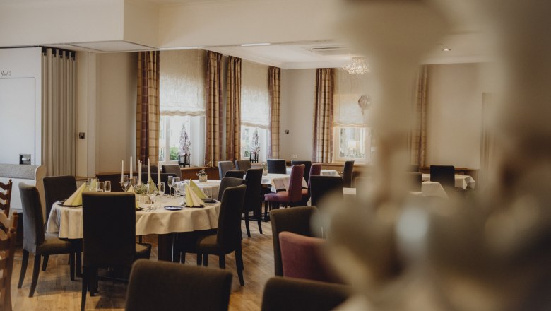Eleganter Speisesaal mit gedeckten Tischen und Kerzen.