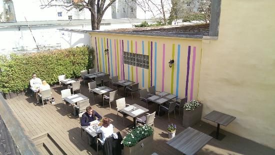 Outdoor area of a café with colorful stripes on the wall and several tables.