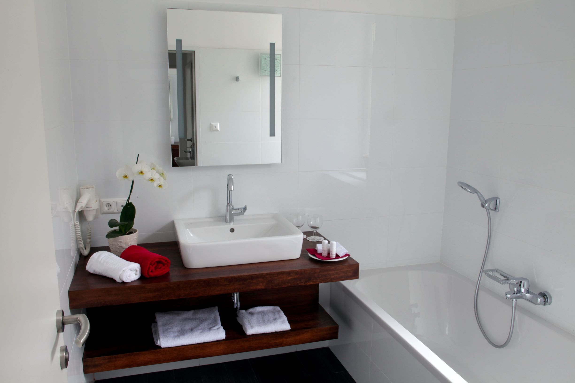 Modernes Badezimmer mit Waschbecken, Spiegel, Badewanne und Handtüchern.