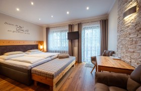 Gemütliches Schlafzimmer mit Doppelbett, Holzmöbeln und Steinwand.