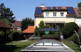 Ein Haus mit Solarpanelen und einem überdachten Pool im Garten.