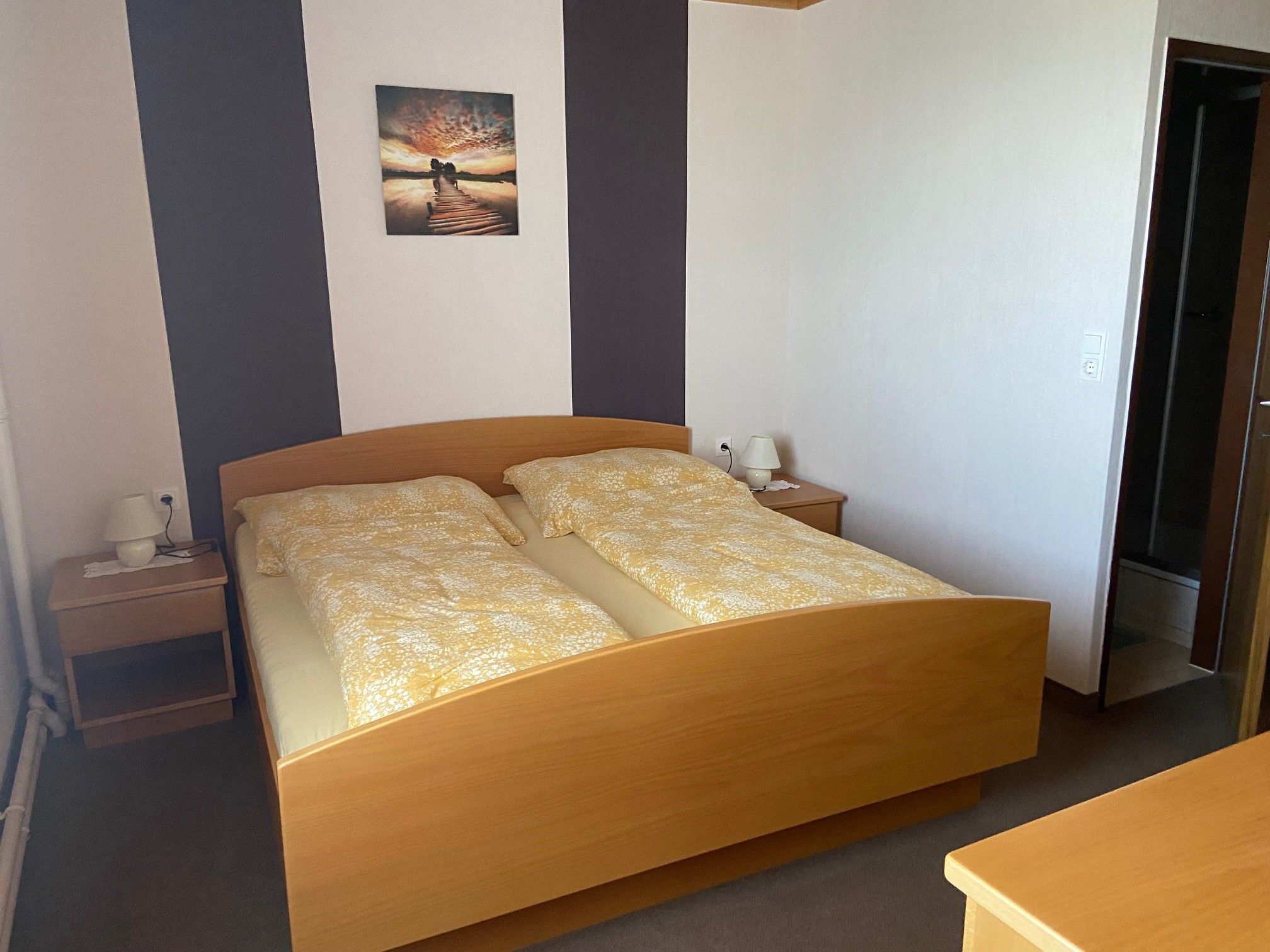 Ein Doppelzimmer mit einem Holzbett, zwei Nachttischen und einem Bild an der Wand.