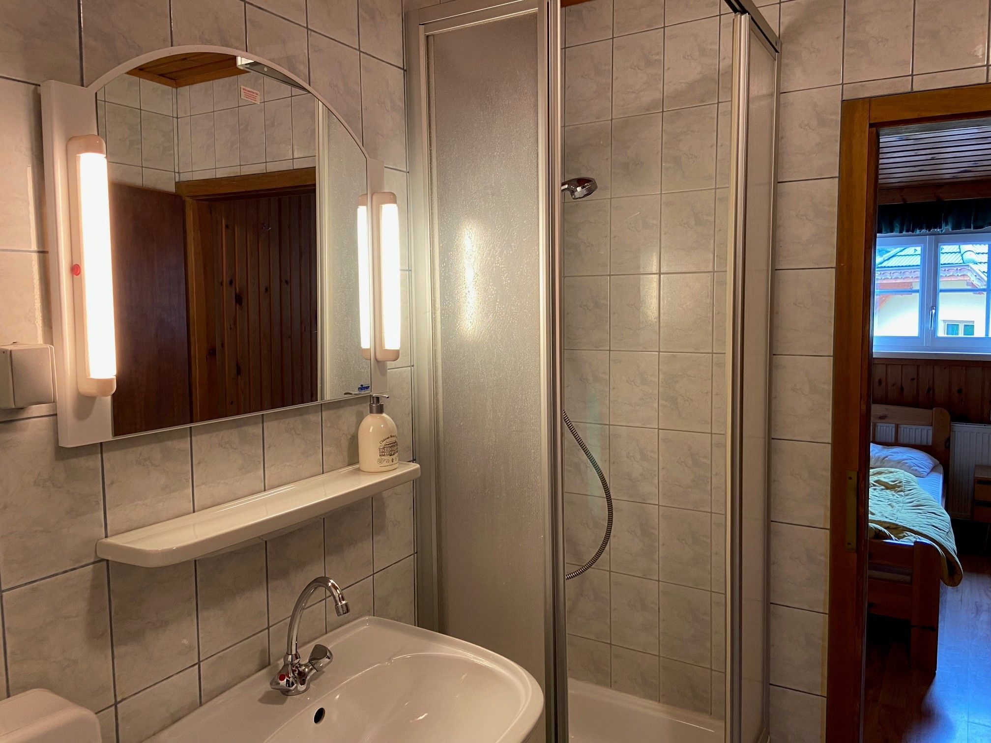 Badezimmer mit Dusche, Waschbecken und Spiegel mit Beleuchtung.